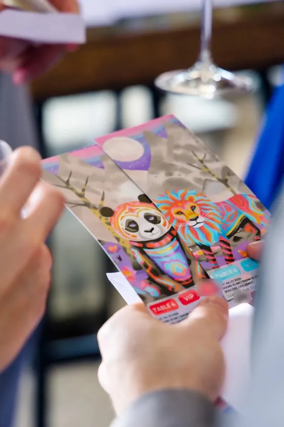 A guest holding illustrated panda and lion ticket cards